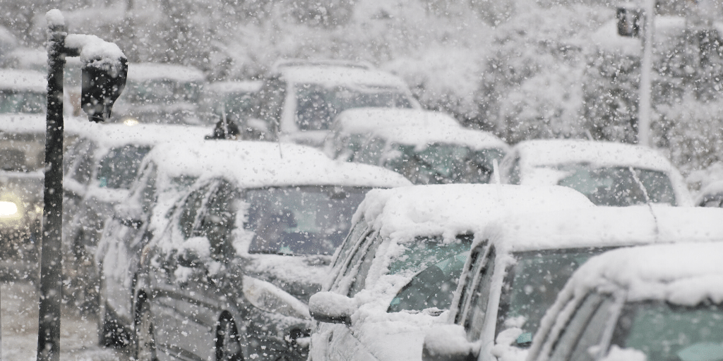 snow falling and covering a row of cars